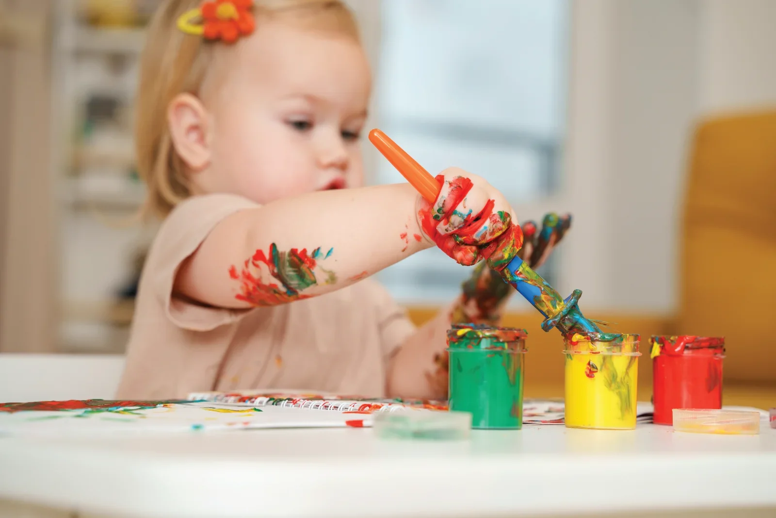 Child painting with colourful paints on table.