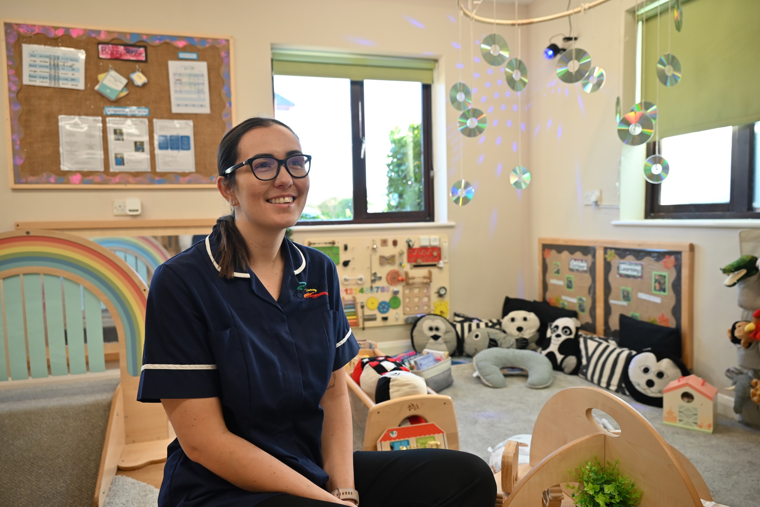 Nursery teacher in classroom with educational toys.